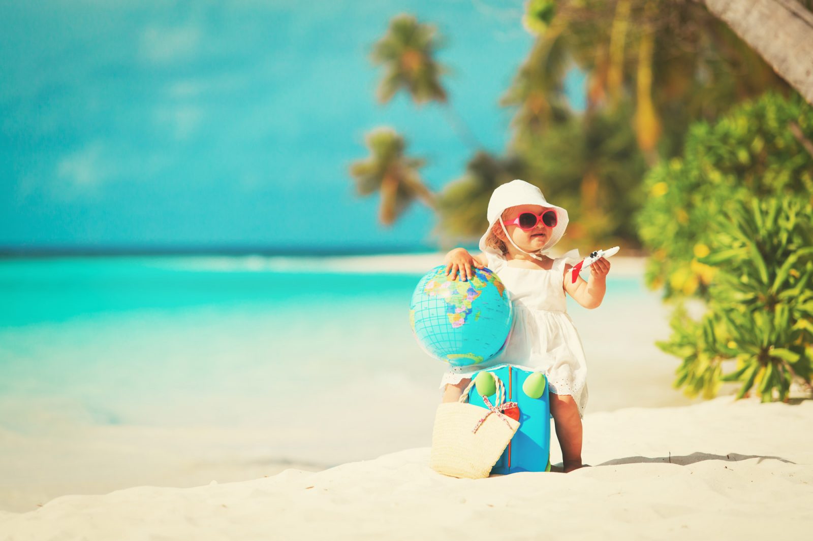 dziecko na piaszczystej plaży z globusem na brzegu morza