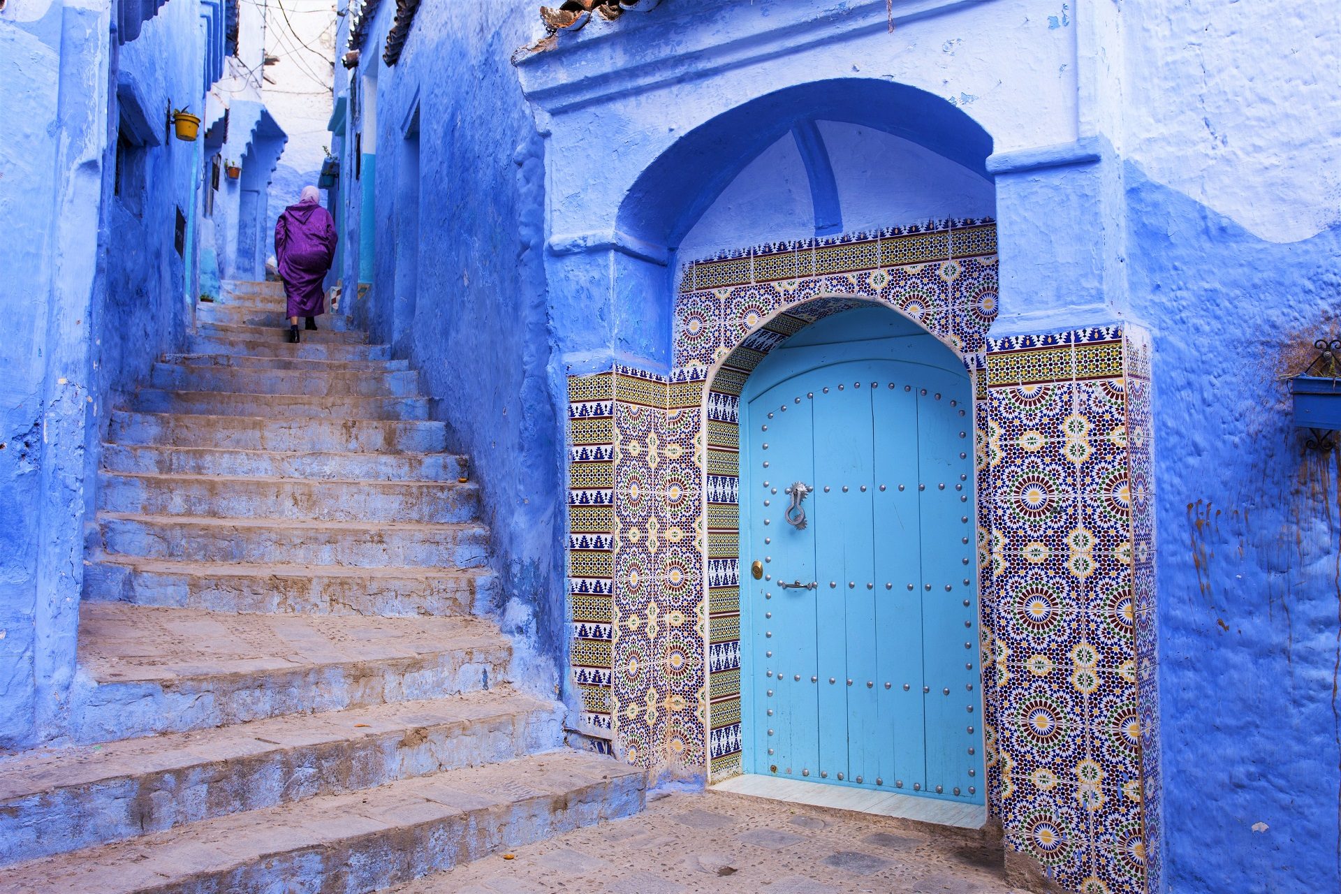 muzułmańska kobieta idzie po schodach w niebieskiej medynie w Maroku w Szafszawan